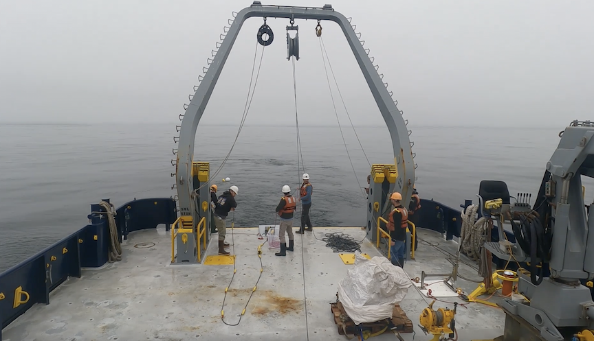 A team of scientists working on the deck of the ship during the deployment of a scientific mooring into the ocean