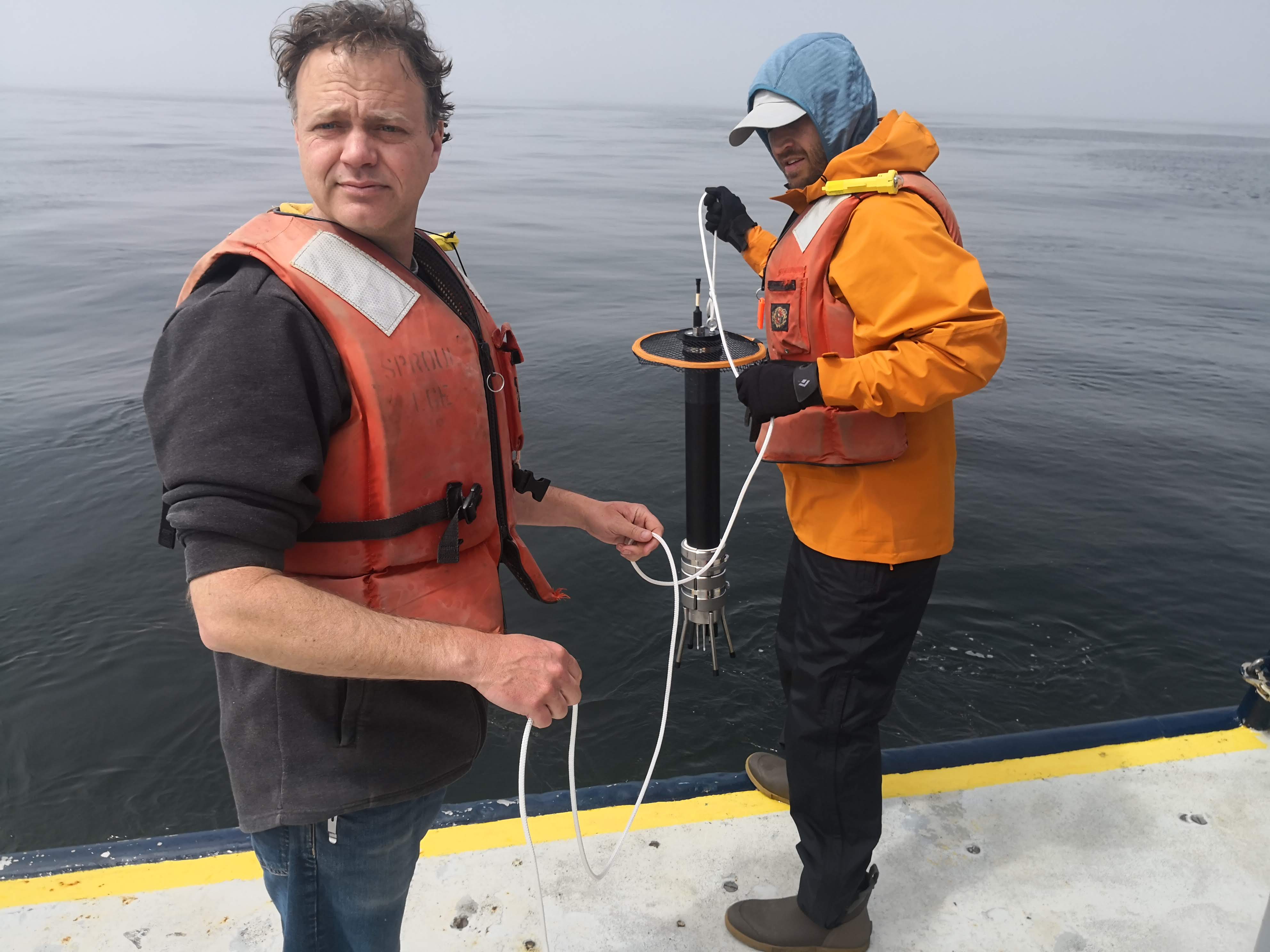 Two scientists at the stern of the ship about to deploy an oceanographic instrument